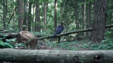 Keçeli şapka ve ekose gömlekli şık genç adam ormanda yürürken akıllı telefon kullanıyor. Vahşi doğaya kaçmak. Macera hisleri ve seyahat tutkusu.