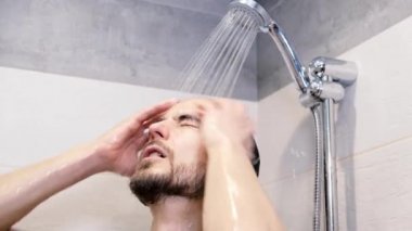 Duşta yıkanan genç adam, vücut bakımı ve kişisel hijyen konsepti. Banyoda sakallı yakışıklı adam suyun altında duş almaktan zevk alıyor. Sabah rutini.