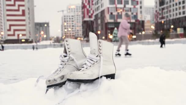 Старые Белые Коньки Выходящие Снег Возле Общественного Катка Современном Городе — стоковое видео