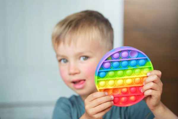 かわいい子供の男の子は 抗ストレスポップそれのフィジェットおもちゃで遊んでいます 子供は感覚ボードゲームを軽減トレンディーなシリコーン圧力を保持シンプルなディンプル ストック画像