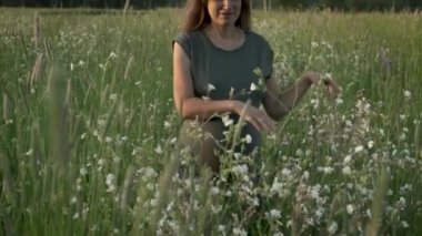 Çiçek açan yaz tarlasında yürüyen yavaş çekim hamile kadın. Bebek beklemenin otantik anları.