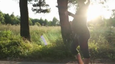 Aktif hamile kadın dışarıda yürüyüş direkleri ile kuzeye yürüme pratiği yapıyor. Bekleyen sağlıklı anne gün batımında yaz parkında antrenman yapıyor..