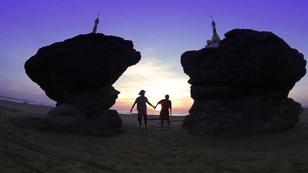 Viagem romântica: casal feliz saltar entre dois pagodes gêmeos na praia de Ngwe Saung, Baía de Bengala, Mianmar (Birmânia). Movimento lento . — Vídeo de Stock