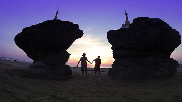 Romantische Reise: glückliches Paar springt zwischen zwei Zwillingspagoden am Strand von Ngwe Saung, Bucht von Bengal, Myanmar (Burma). Zeitlupe. — Stockvideo