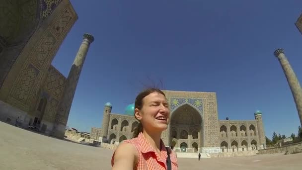 SAMARKAND, UZBEKISTÁN - 22 DE SEPTIEMBRE DE 2015: Encantada turista en la Plaza Registan, admirando la arquitectura de Asia Central el 22 de septiembre, en Samarcanda, Uzbekistán . — Vídeos de Stock