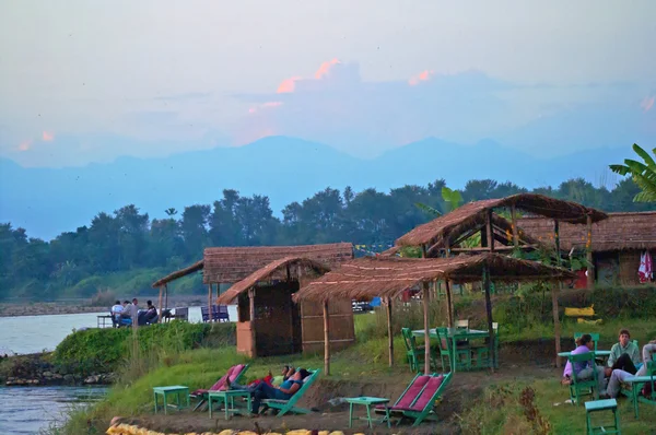 Turiștii se odihnesc lângă râul sălbatic în timpul apusului de soare în Parcul Național Chitwan, Nepal — Fotografie, imagine de stoc