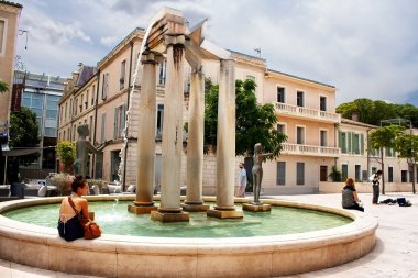 Unidentified tourists near fountain on the square of Assas, Nimes, France clipart