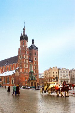 Krakow, Polonya - 29 Aralık 2013: At arabası ana kare Krakow şehir Mariacki Kilisesi önünde. Krakow turistler arasında çok popüler bir at binmek bir satır boşluğu içinde sürüyor