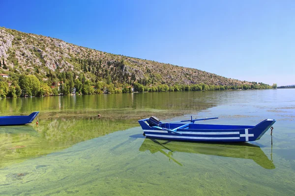 Barco de pesca de madeira velho tradicional azul com bandeira de Greece no lago Orestiada em cidade de Kastoria de Greece do norte — Fotografia de Stock