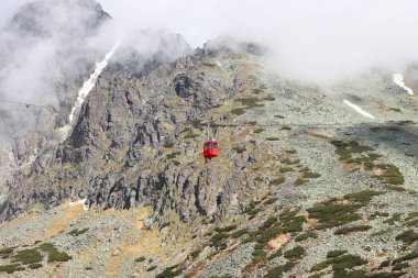 Lomnicky 'e giden kırmızı teleferik kabini High Tatras, Slovakya' nın arka planına dikiliyor