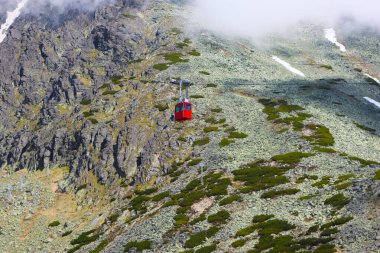 Lomnicky 'e giden kırmızı teleferik kabini High Tatras, Slovakya' nın arka planına dikiliyor