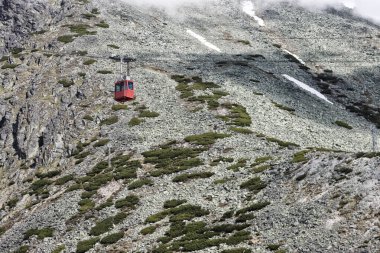 Lomnicky 'e giden kırmızı teleferik kabini High Tatras, Slovakya' nın arka planına dikiliyor
