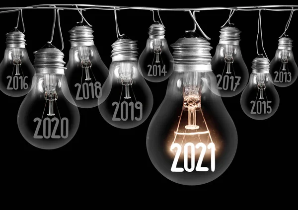 Horizontal group of shining light bulb with fiber in a shape of New Year 2021 and dimmed light bulbs with years passed isolated on black background.