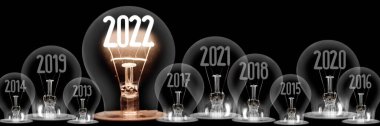 2022 yılına uygun lifli parlayan ampullerden oluşan yatay bir grup ve siyah arkaplanda yıllarca izole edilmiş koyu renk ampuller..