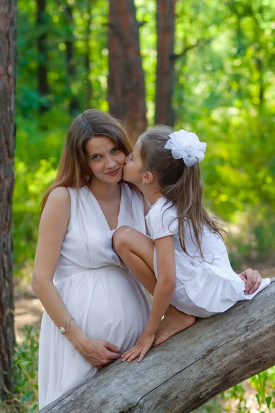 Little daughter kissing her pregnant mother outdoors — Stock Photo, Image