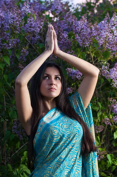 Beautiful woman praying in lilac bushes at sunset — Stock Photo, Image