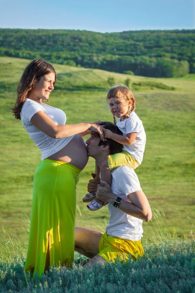 Feliz família grávida beijando na natureza — Fotografia de Stock