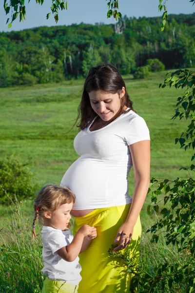 Mulher grávida e sua filha na natureza — Fotografia de Stock