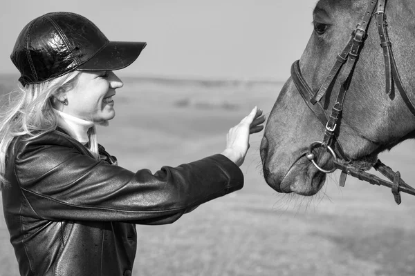 Mulher de cavalo acariciando a cabeça do cavalo, preto e branco — Fotografia de Stock