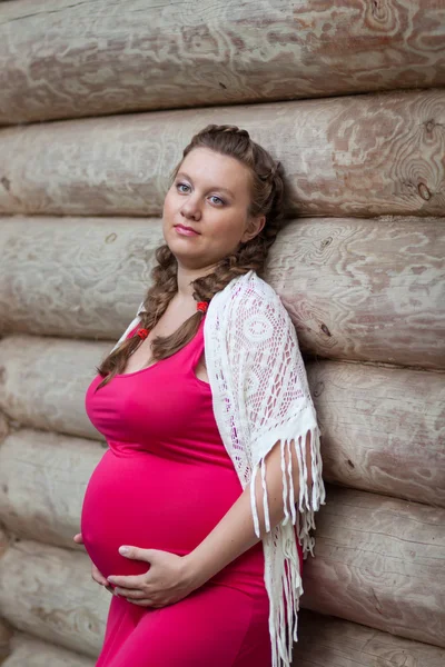 Pregnant woman in red dress on a background of the old house — Stock Photo, Image