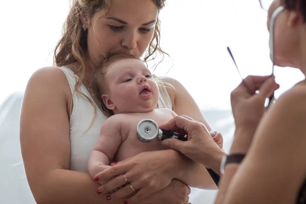 Arzt untersucht neugeborenes Mädchen mit Stethoskop lizenzfreie Stockbilder