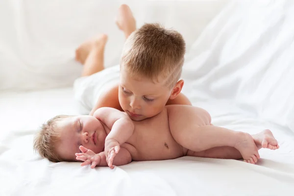 Die erste Liebe. Kleiner Junge beobachtet seine neugeborene Schwester im Haus Stockbild