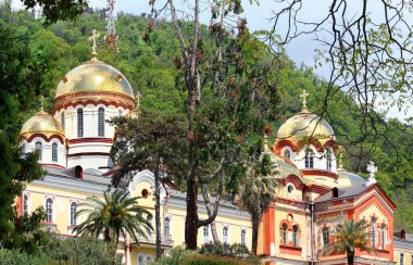 Güney ağaçlarının arasında altın kubbeleri olan manastır tapınağı.