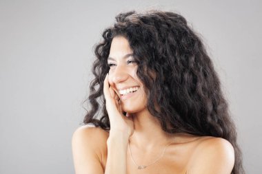 Uzun kıvırcık saçlı, stüdyo portresi olan güzel esmer kız. Gülen yüz ifadesi.