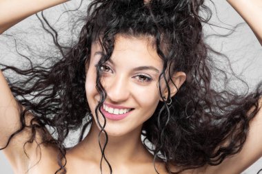 Uzun ıslak saçlı güzel esmer kız, stüdyo portresi. Çok mutlu bir gülümseme..
