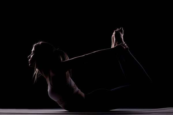 Beautiful caucasian girl posing yoga in shadow, side lit