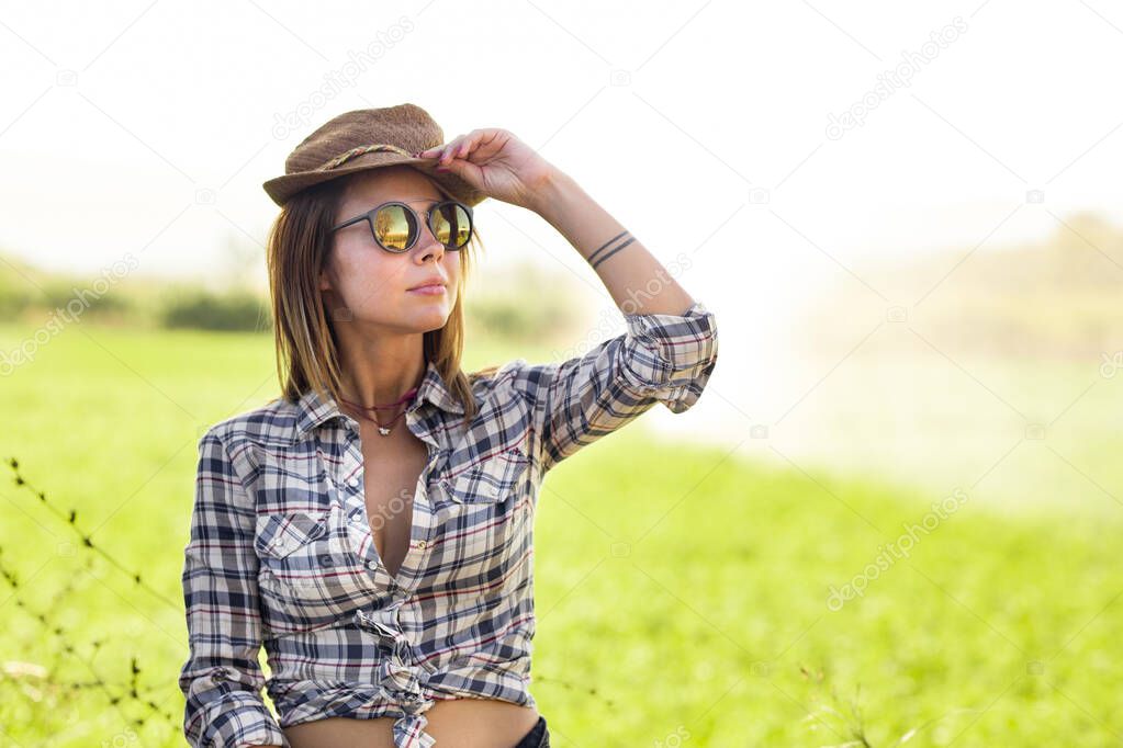 beautiful girl with hat wearing shirt in a field with water sprinklers