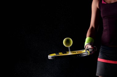 Tenis topu rakette zıplıyor. Toprak ya da magnezyum tozları havada görülebilir. Raket tutan kadın oyuncu.