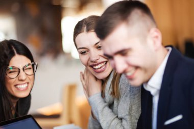 Genç ve başarılı iş adamları bir kafede yaratıcı bir toplantı yapıyorlar. Gülümseyen ve gülen yüz ifadeleri.