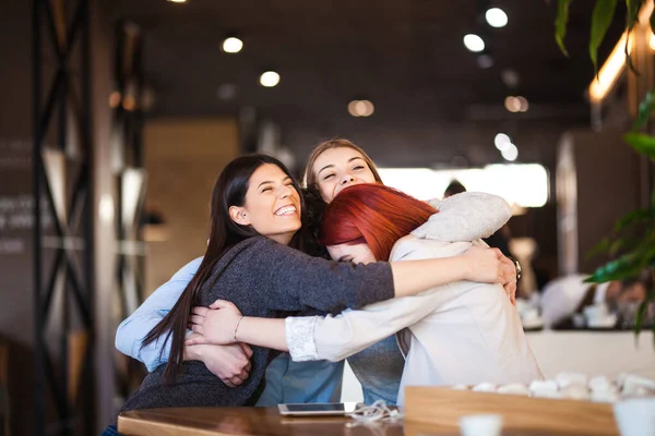 Four friends at a cafe celebrating and hugging. Successful young people