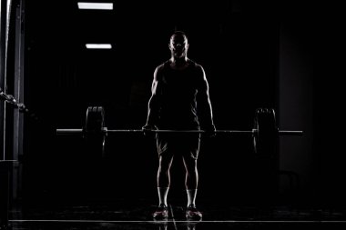 Halter kaldıran bir sporcu. Kaslı bir adamın silueti..