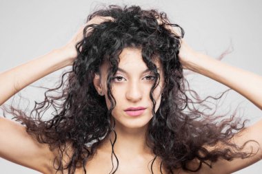 Uzun ıslak saçlı güzel esmer kız, stüdyo portresi. Ciddi yüz ifadesi.