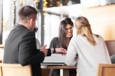 Genç ve başarılı iş adamları bir kafede toplantı yapıyorlar. Gülümseyen ve gülen yüz ifadeleri.
