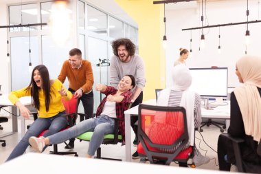 İş arkadaşları iş yerinde eğleniyorlardı. Tekerlekli sandalyedeki erkekleri iten kızlar. Çok ırklı başarılı bir şirket kurma grubu