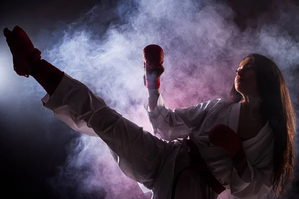 Chica Ejercicio Karate Pierna Kick Contra Rojo Niebla Fondo — Foto de Stock