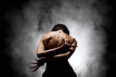 Yarı siluet modern balerin esmer arka planda dumanla poz veriyor.