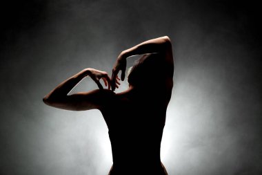 Siluet modern balerin esmer arka planda dumanla poz veriyor.