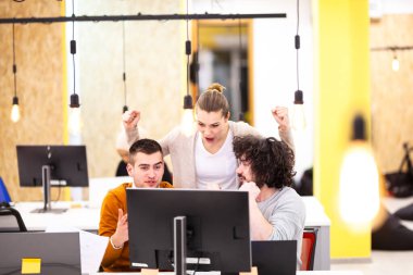 Dekoratif ampulleri olan modern bir ofiste üç beyaz iş arkadaşı tezahürat yapıyor.