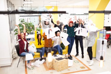 Modern ofis işyerindeki çok ırklı başarılı iş arkadaşlarının oluşturduğu takım başarıyı kutlamak için kağıt fırlatıyor. Çeşitlilik mutluluk kavramı.