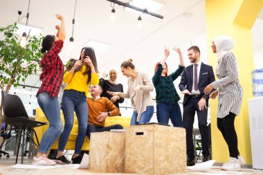 Modern ofis işyerinde dans eden ve başarıyı kutlayan başarılı çok ırklı iş arkadaşları takımı. Çeşitlilik mutluluk kavramı.