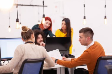 Modern bir ofis alanında masaüstü bilgisayarları üzerinde çalışan çok ırklı meslektaşlardan oluşan bir grup.