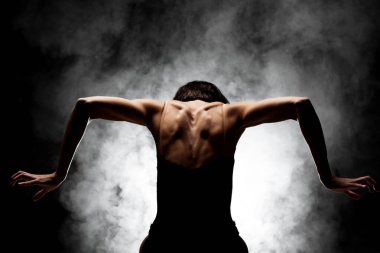 Yarı siluet modern balerin esmer arka planda dumanla poz veriyor.