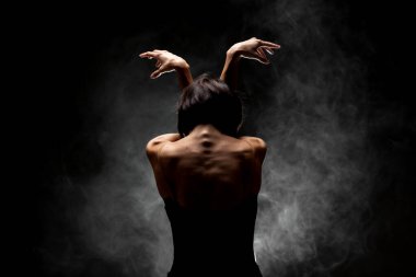 Yarı siluet modern balerin esmer arka planda dumanla poz veriyor.