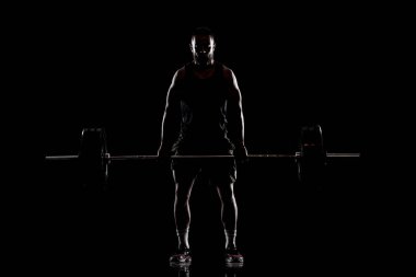 Halter kaldıran bir sporcu. Kaslı bir adamın silueti..
