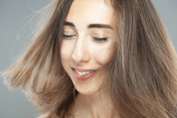 空気中の髪の美しいブルネットの女の子 スタジオの肖像画 笑顔の表情 — ストック写真