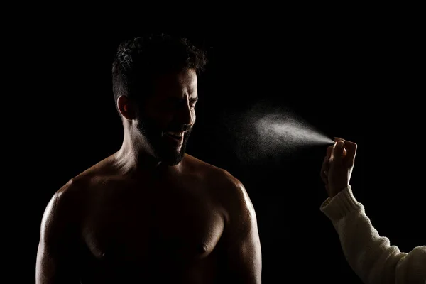 侧光肌肉白种人轮廓 运动员在黑色背景下喷洒水或香水 — 图库照片